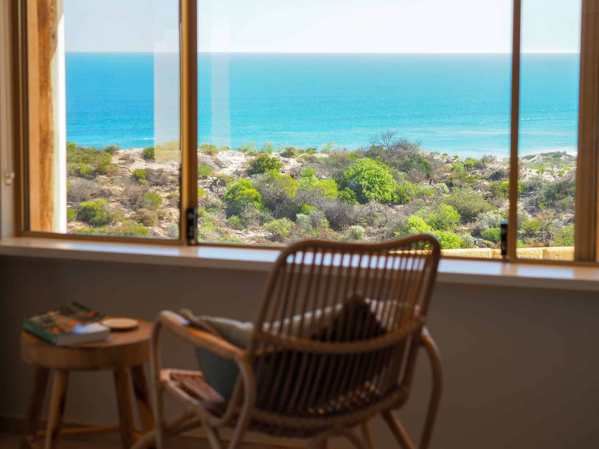 A rocking chair by the window in the master bedroom at The Glass House WA Airbnb in Greenough, Western Australia