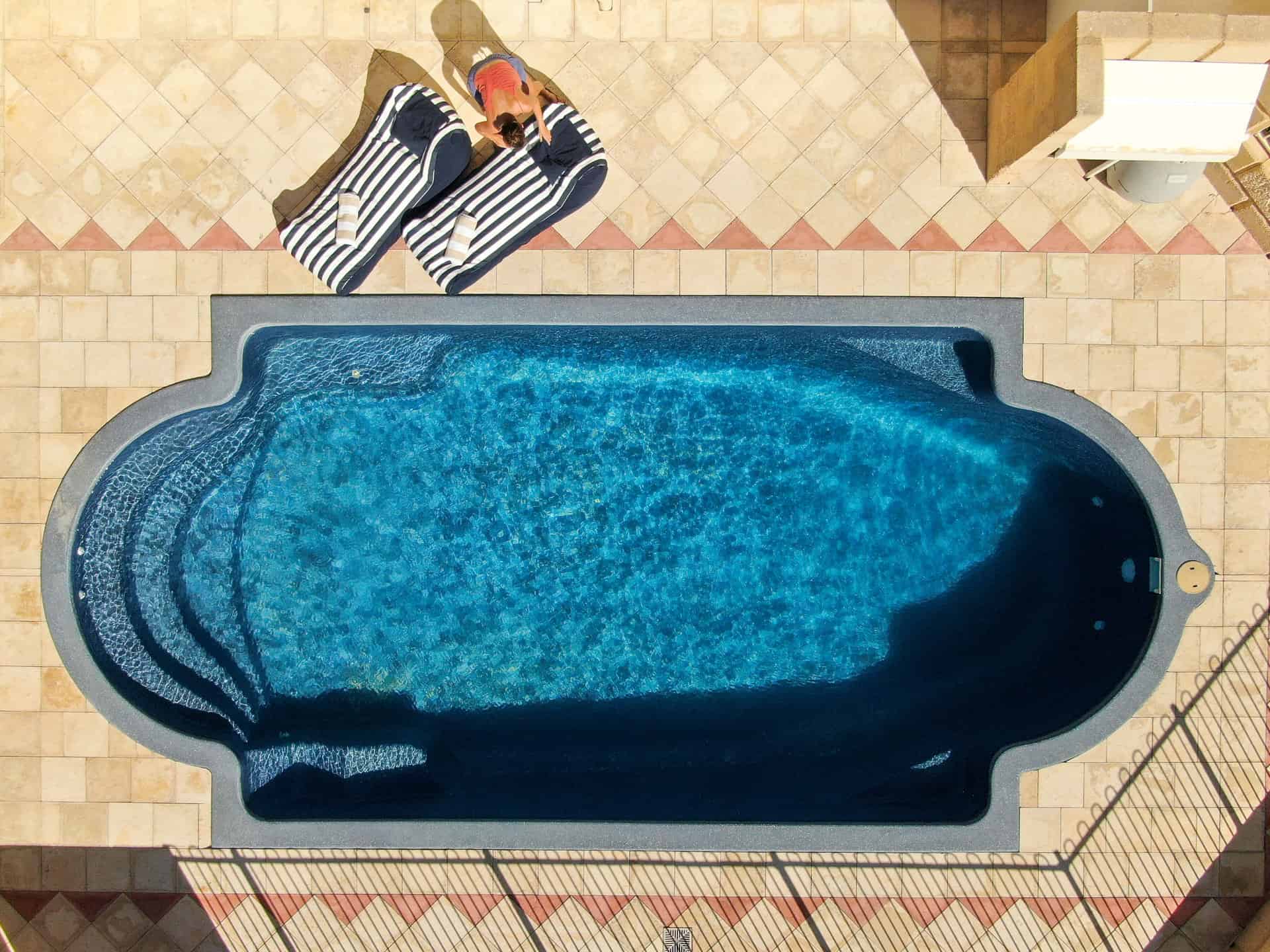 Drone shot of the swimming pool and striped beanbags at The Glass House WA Airbnb in Greenough, Western Australia