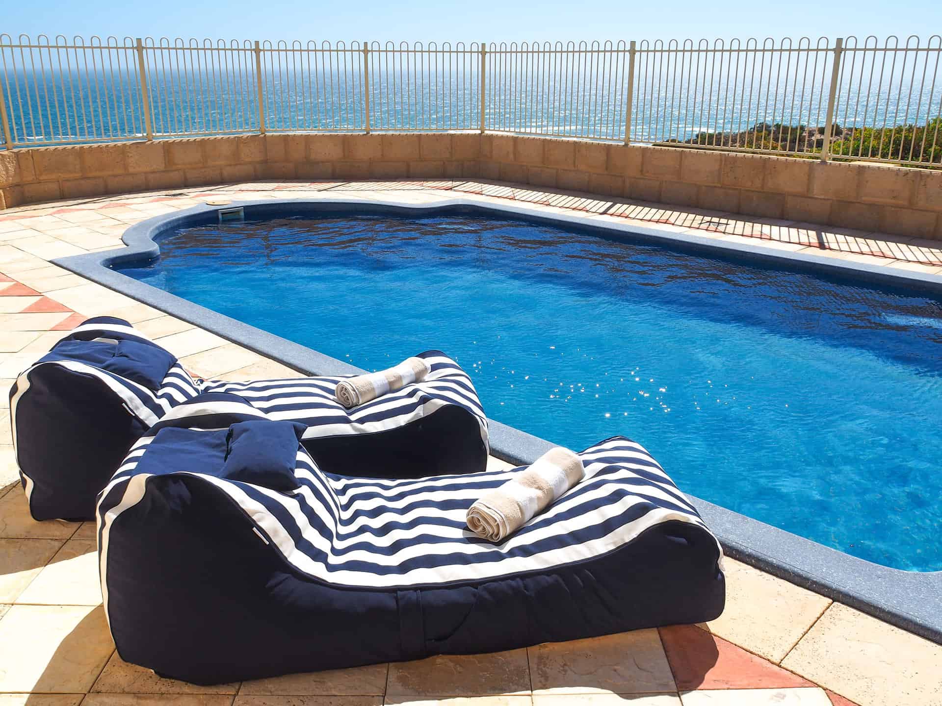 The swimming pool and striped beanbags at The Glass House WA Airbnb in Greenough, Western Australia