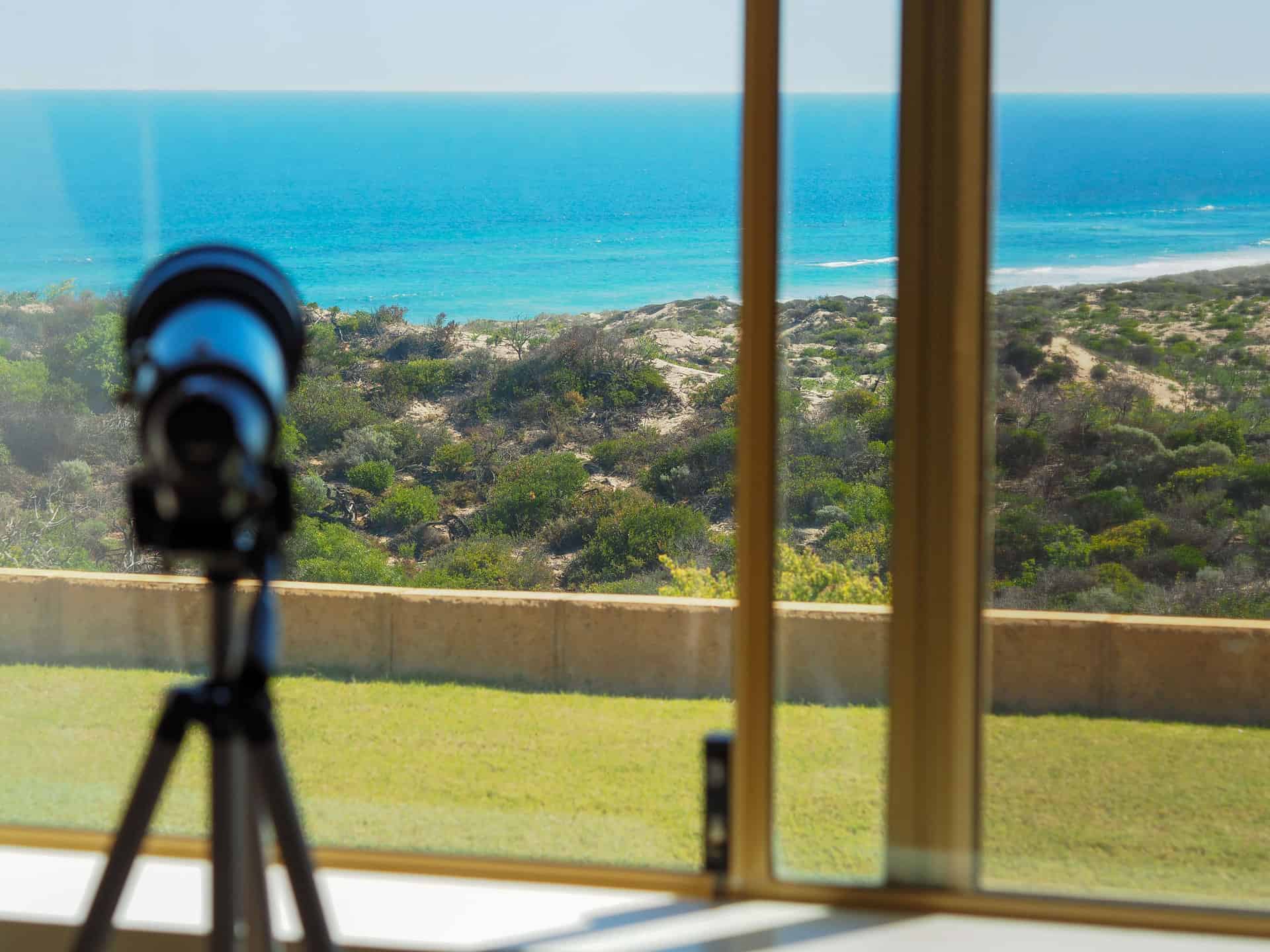 A telescope by the window at The Glass House WA Airbnb in Greenough, Western Australia